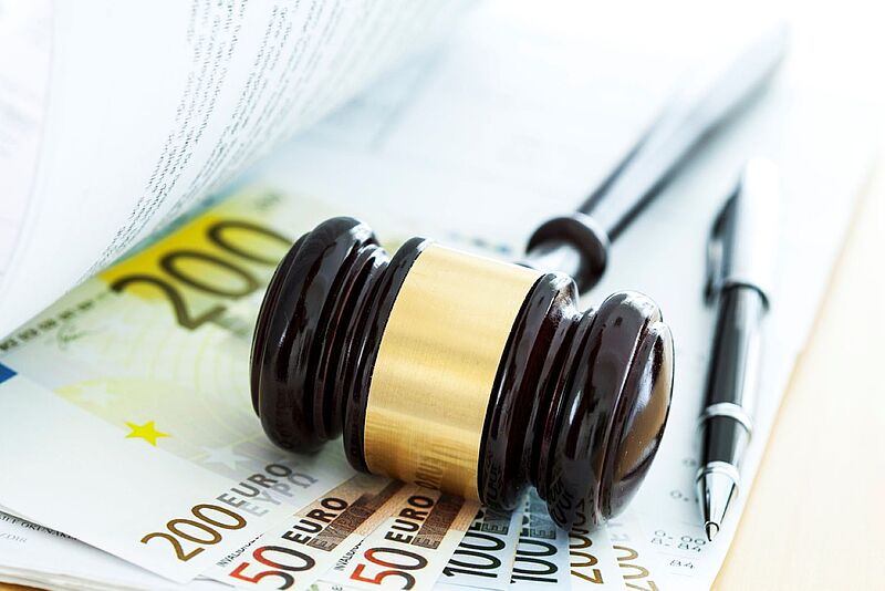 Richterhammer auf Eurobanknoten und Dokumenten, daneben ein Stift.