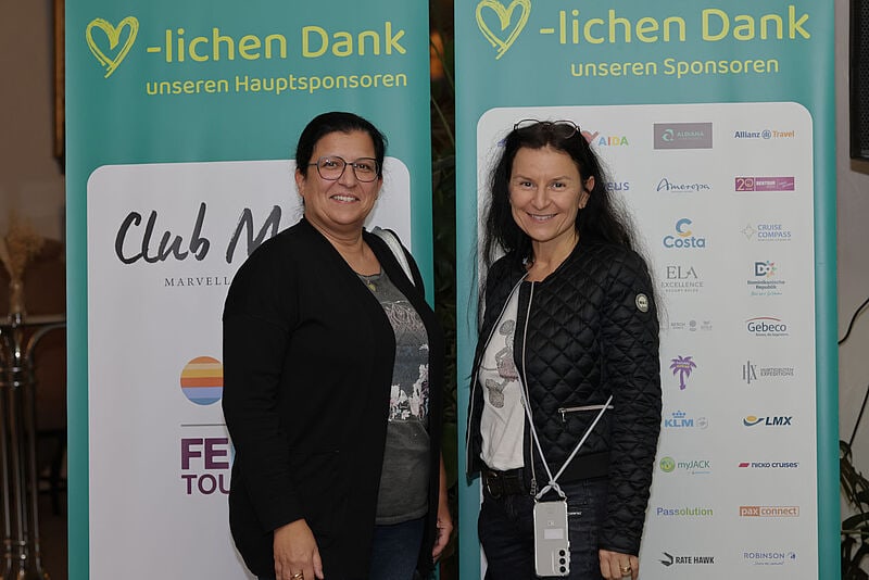 Zwei Teilnehmerinnen posieren vor der Sponsorenwand der Tagung. Foto: Chris Fruehe/RTK