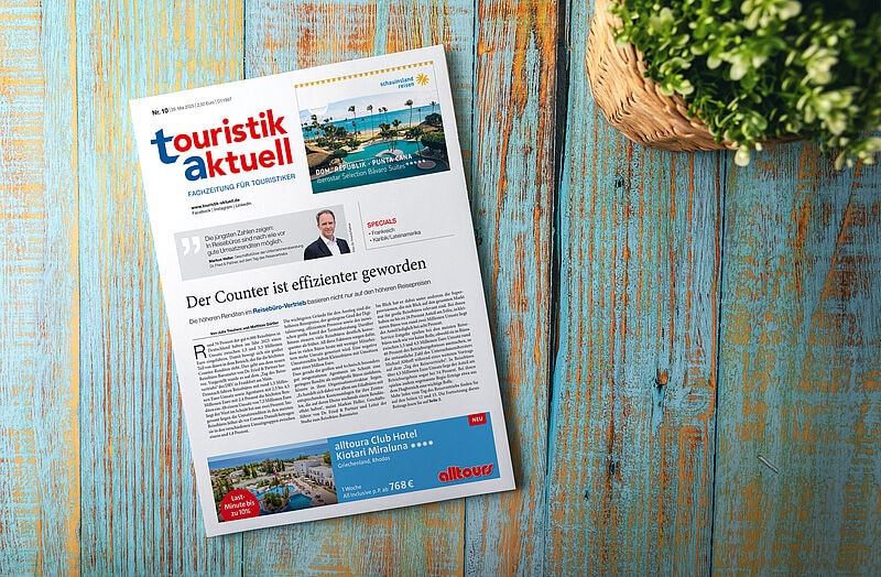 Titelseite der Fachzeitung „touristik aktuell“ (Ausgabe Nr. 10, 20. Mai 2025) auf einem blauen Holztisch mit Pflanzenkorb. Haupttitel: „Der Counter ist effizienter geworden“, dazu ein Artikel über Umsatzrenditen im Reisebüro-Vertrieb. Oben Werbung für Schmetterling Reisen (DOM-REP – Punta Cana), unten Werbung für alltours (Hotel auf Rhodos).