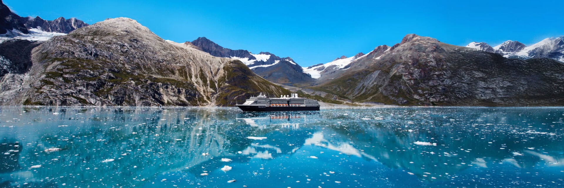 Ein Kreuzfahrtschiff mit dunklem Rumpf und weißem Aufbau passiert in Alaska gewaltige Gletscher.