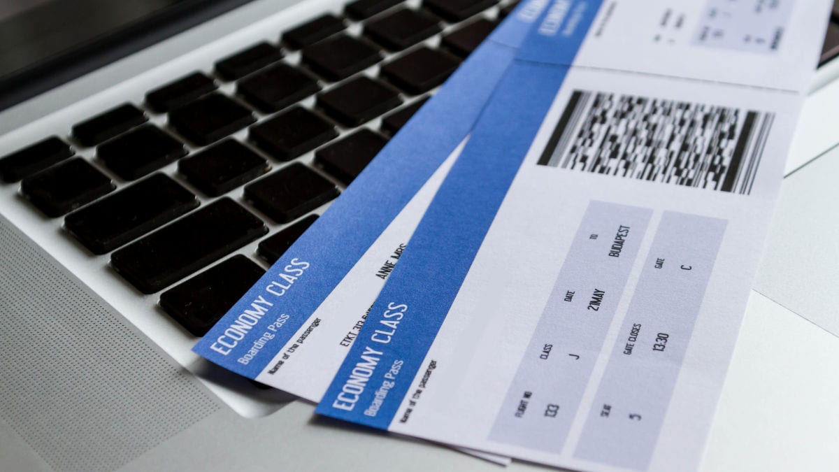 Zwei Flugtickets in der Economy Class liegen auf einer Laptop-Tastatur und zeigen Reisedaten sowie einen Barcode. Die Bordkarten sind für einen Flug nach Budapest ausgestellt.