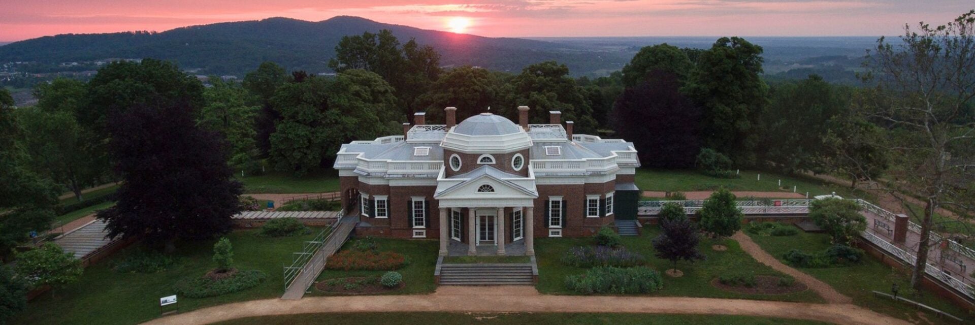 Luftaufnahme von Monticello in Charlottesville, Virginia, vor einer hügeligen Landschaft bei Sonnenaufgang.