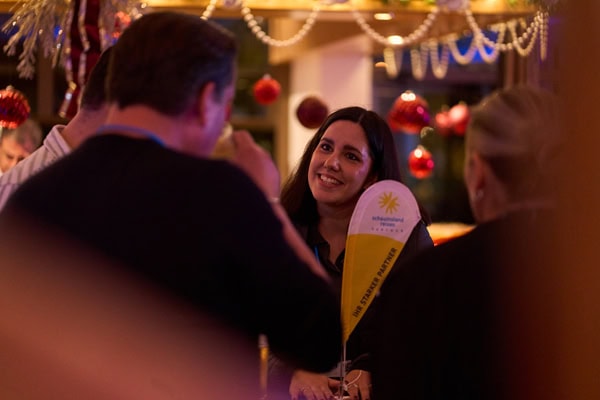 Eine Frau sieht einen Mann an, der mit dem Rücken zur Kamera steht und lächelt. Vor ihr steht ein Wimpel mit dem Aufdruck Ihr starker Partner