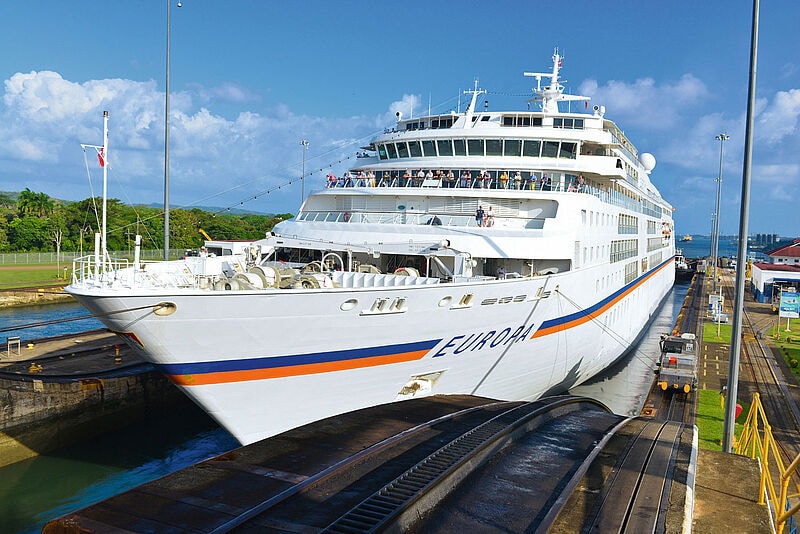 Kreuzfahrtschiff MS Europa von Hapag-Lloyd in einer Schleuse des Panamakanals, umgeben von tropischer Vegetation.