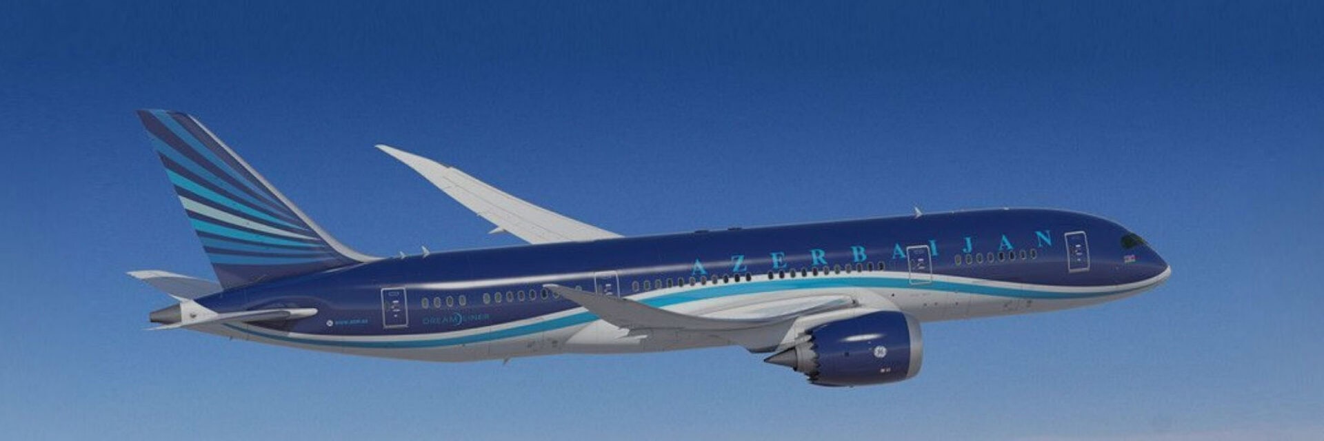 Passagierflugzeug der Azerbaijan Airlines im Flug vor klarem, blauem Himmel. Die Maschine ist seitlich zu sehen, mit dunkelblauer Lackierung, türkis-weißen Streifen, Schriftzug „Azerbaijan“ am Rumpf und modernen Triebwerken unter den Tragflächen.