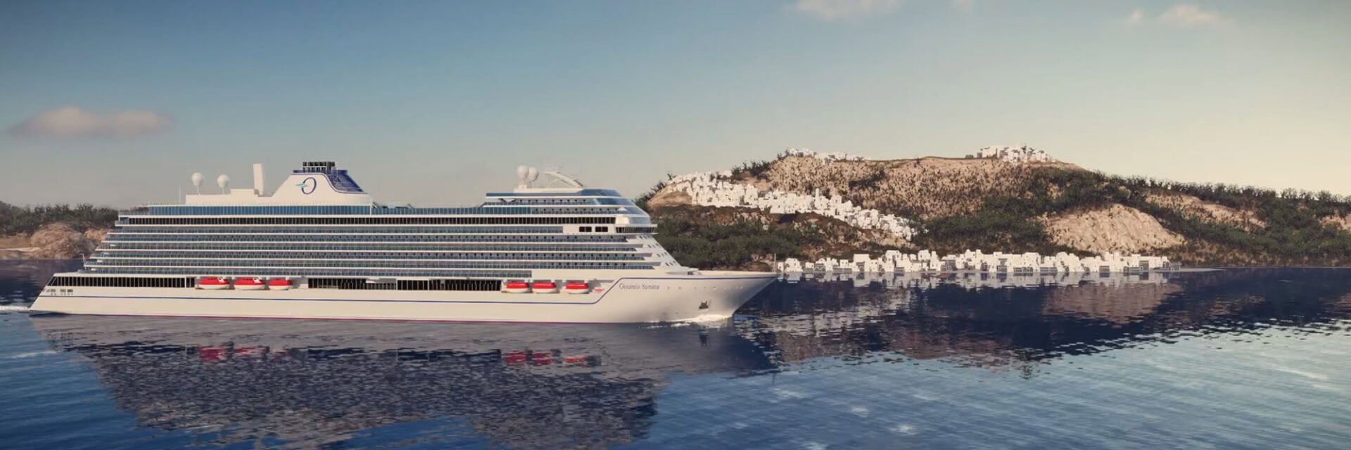 Auf dem Bild ist ein modernes Kreuzfahrtschiff der Oceania Cruises zu sehen, das ruhig auf dem blauen Meer vor einer felsigen Küste mit weißen Häusern entlang der Hügel fährt. Das Kreuzfahrtschiff spiegelt sich im klaren Wasser, während am Horizont ein sonniger Himmel mit wenigen Wolken zu erkennen ist.