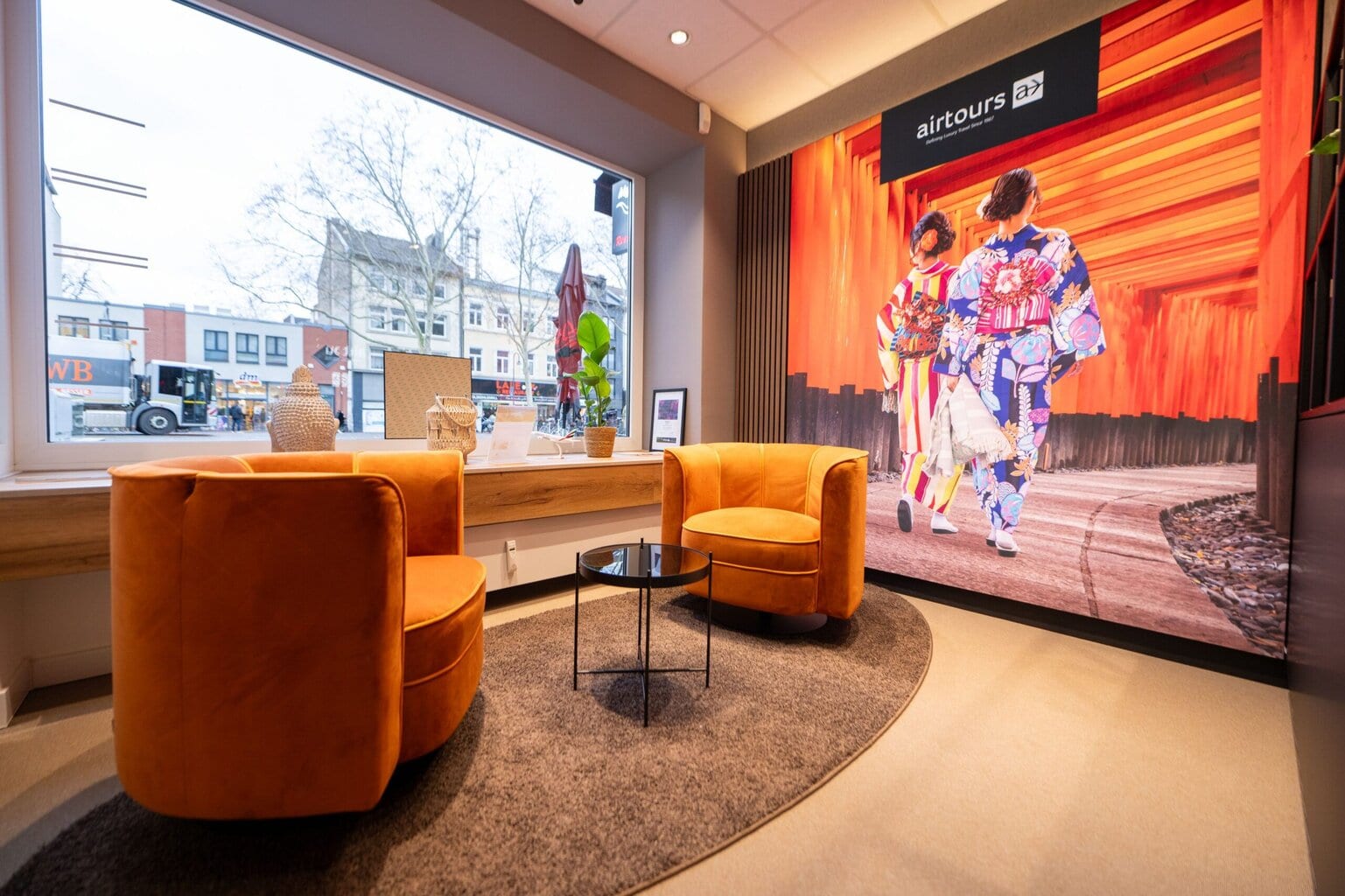 Gemütlicher Sitzbereich der Airtours Lounge mit zwei Sesseln, Beistelltisch und großem Wandmotiv.