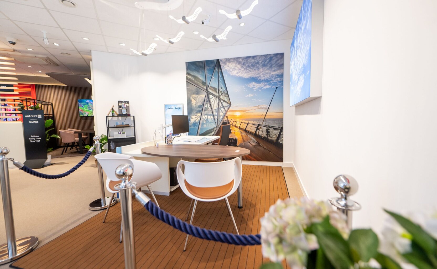 Weiterer Blick auf den modern gestalteten Kreuzfahrtbereich mit Beratungstischen und großformatigem Wandmotiv.
