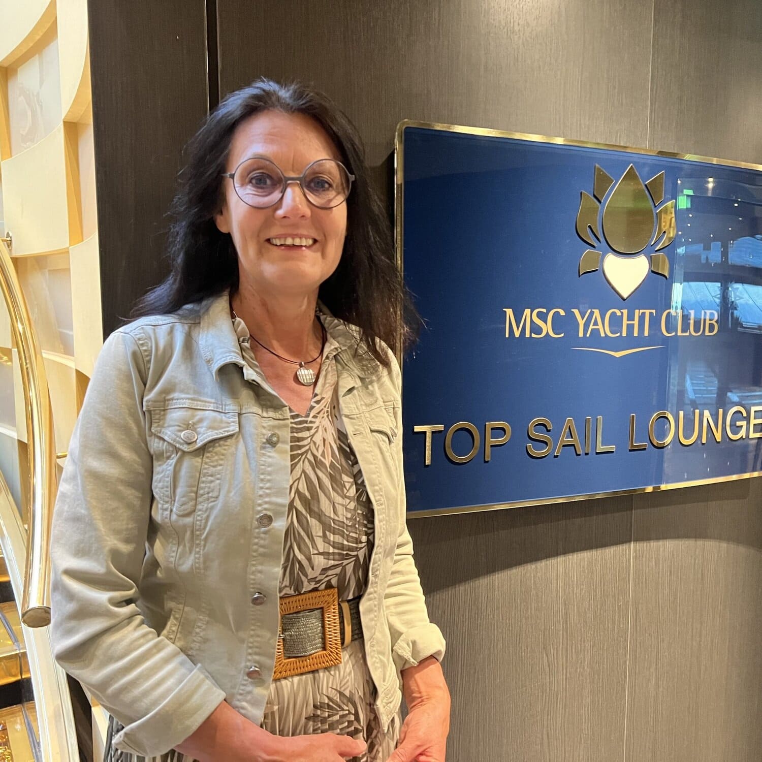 Eine Frau mit runder Brille und dunklen halblangen Haaren vor einem Schild mit MSC Yacht Club