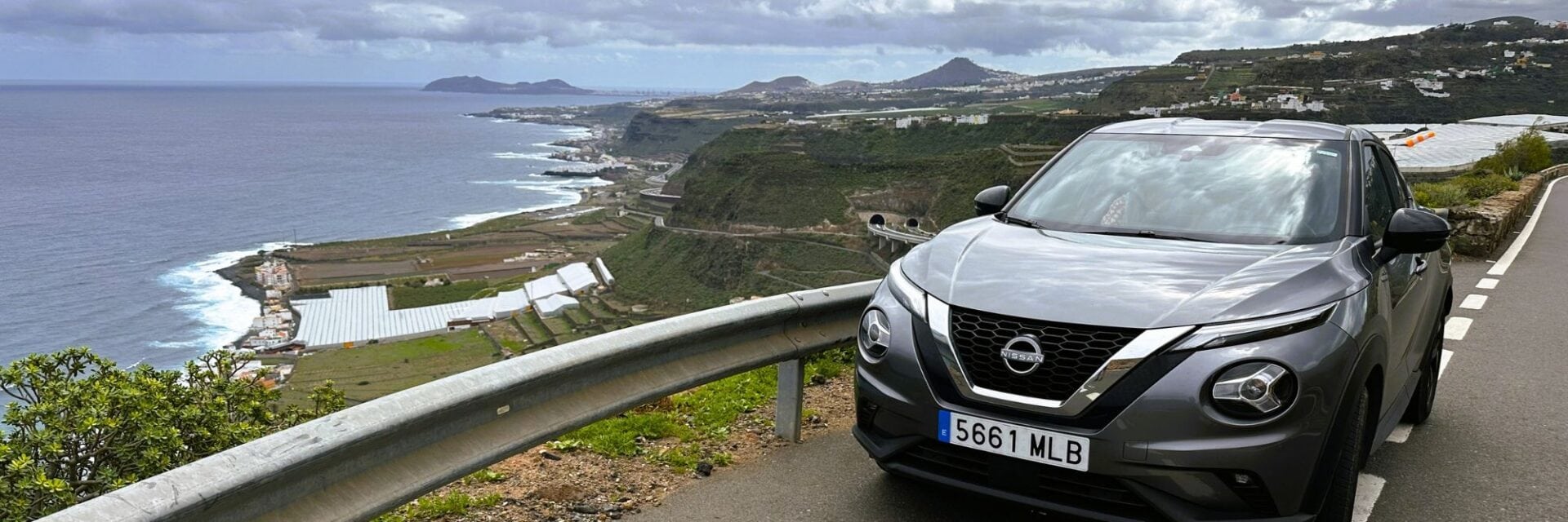 Auto geparkt am Straßenrand, im Hintergrund Ausblick auf Klippen und Meer, aufgenommen auf Teneriffa.