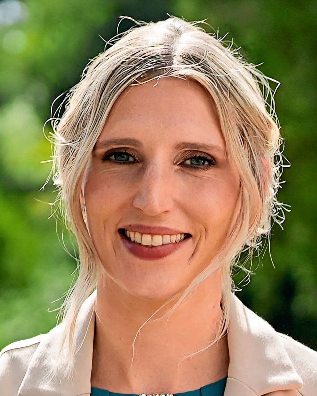 Eine junge Frau mit Abend-Make-up und blonden Haaren lacht in die Kamera