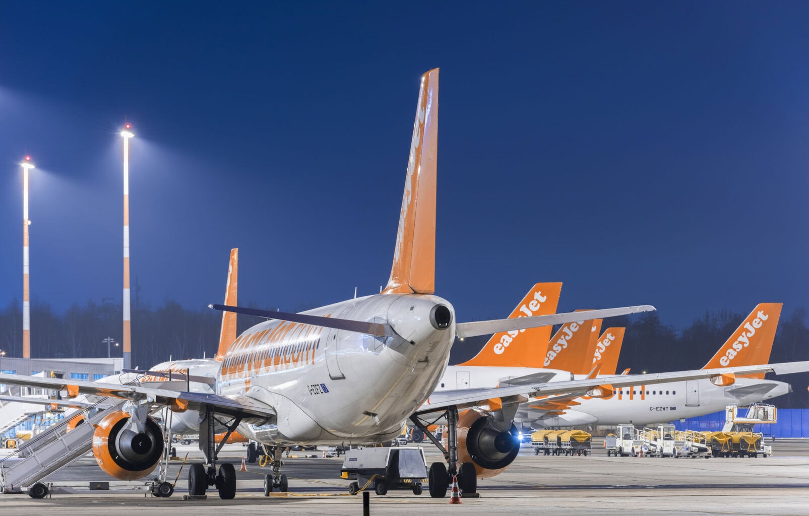 Passagierflugzeuge der Airline Easyjet mit orange-weißer Lackierung und gut sichtbarem Schriftzug auf dem Vorfeld eines Flughafens am Abend zur Blauen Stunde