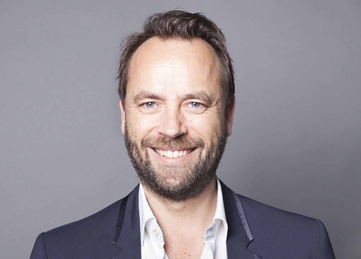 Porträtfoto eines Mannes im Business-Outfit mit Sakko und offenem Hemdkragen vor neutralem grauen Hintergrund, ideal für die Darstellung eines Geschäftsführers oder Managers.