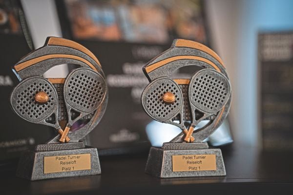 Zwei Pokale aus zwei sich  Padel-Schlägern, in grau und gold