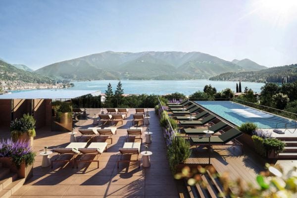 Luxuriöse Terrasse mit Sonnenliegen und Pool im Falkensteiner Hotel am Gardasee in Italien, umgeben von mediterranen Pflanzen und mit Panoramablick auf den See und die Berge.