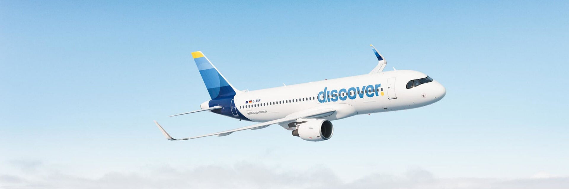 Ein modernes Passagierflugzeug von Discover Airlines fliegt am blauen Himmel, deutlich sichtbar mit dem markanten Discover-Logo auf dem Rumpf. Das Flugzeug gehört zur Lufthansa Group und hebt sich klar vor dem wolkenlosen Hintergrund ab.
