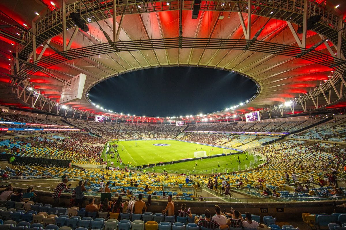 Innenansicht des Maracanã-Stadions in Rio de Janeiro mit beleuchtetem Spielfeld und Zuschauern auf den Rängen während eines Fußballspiels