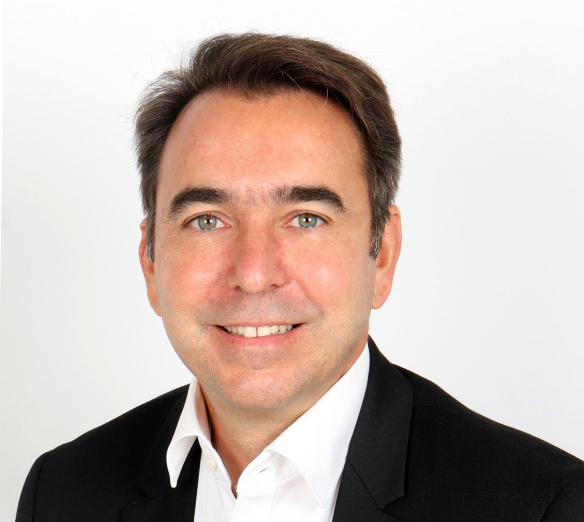 Porträtfoto eines Mannes im Business-Outfit vor weißem Hintergrund; der Mann trägt einen schwarzen Anzug und ein weißes Hemd, das Bild eignet sich zur Illustration von Themen wie Geschäftsleute, Manager oder Unternehmensführung.