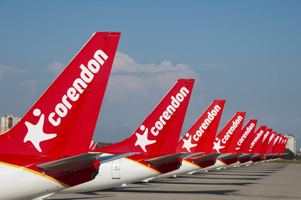 Reihe von roten Heckflossen der Corendon Airlines mit weißem Logo auf Flughafen-Vorfeld aufgereiht.