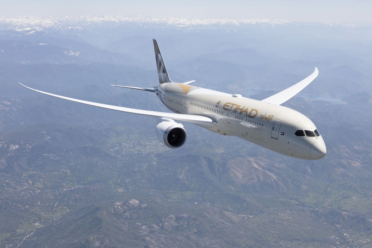 Ein Flugzeug vom Typ Boeing 787 Dreamliner von Etihad Airways fliegt über eine Gebirgslandschaft.