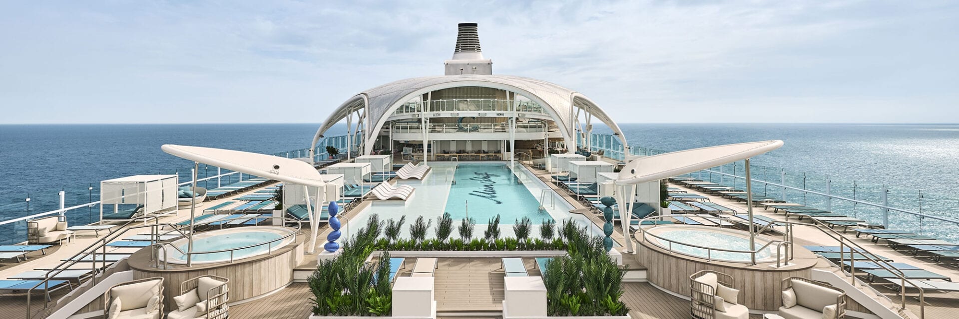 Zu sehen ist das Pooldeck eines modernen Kreuzfahrtschiffes mit einer großen gewölbten Kuppel darüber.