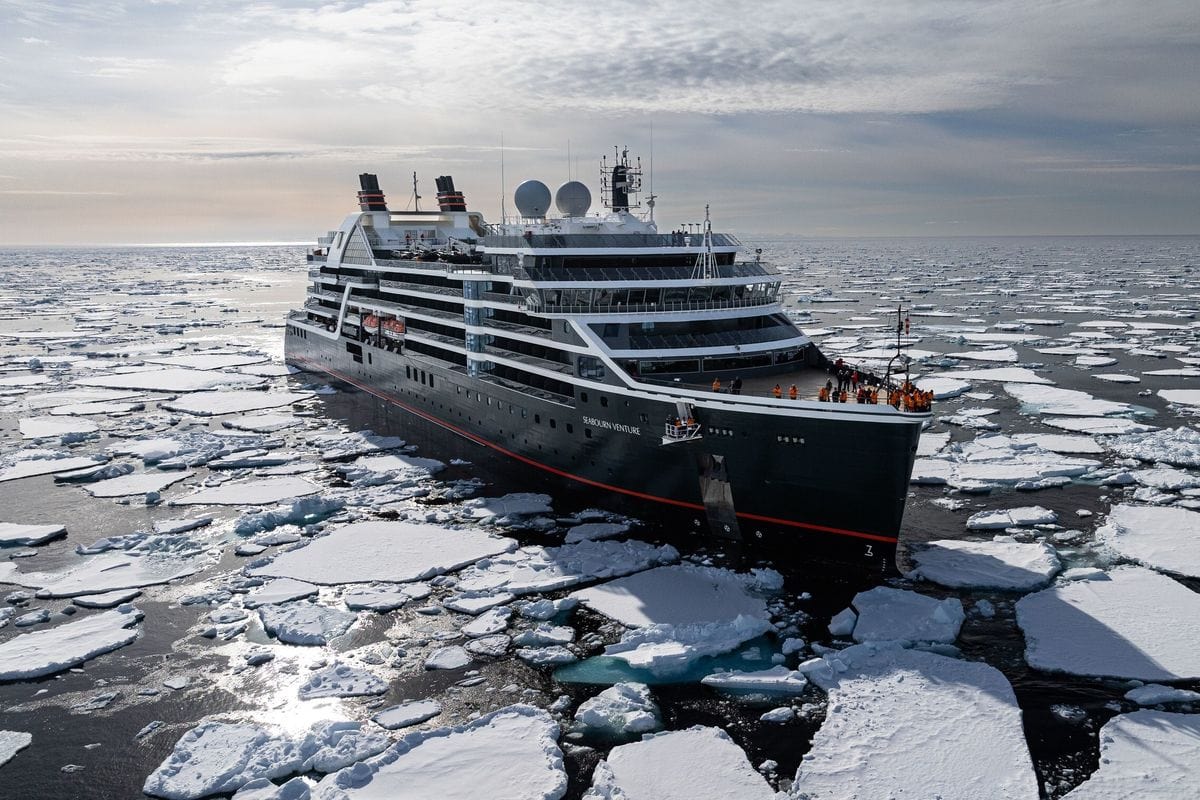 Expeditionsschiff Seabourn Venture fährt durch aufgebrochenes arktisches Meereis unter bewölktem Himmel.
