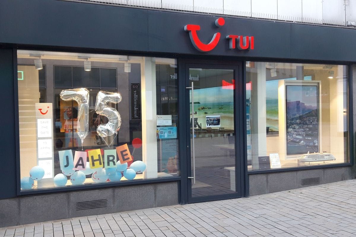 Tui Reisebüro in Herford mit Schaufensterdekoration zum 75‑jährigen Jubiläum: silberne „75“-Ballons, bunte Buchstaben „JAHRE“ und blaue Luftballons vor der Glasfront, über dem Eingang das rote Tui-Logo.