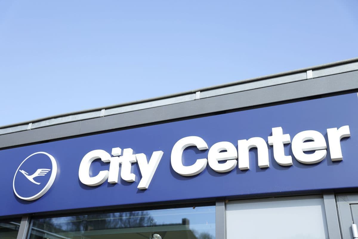 Außenansicht eines Lufthansa City Center mit blauem Firmenschild, Lufthansa-Logo und weißer Aufschrift „City Center“.