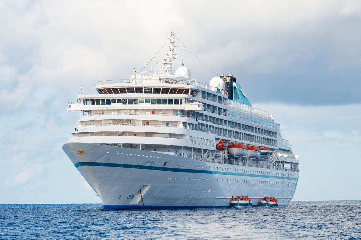 Das Kreuzfahrtschiff Amera mit weißem Rumpf und türkisfarbenen Elementen fährt auf dem offenen Meer.