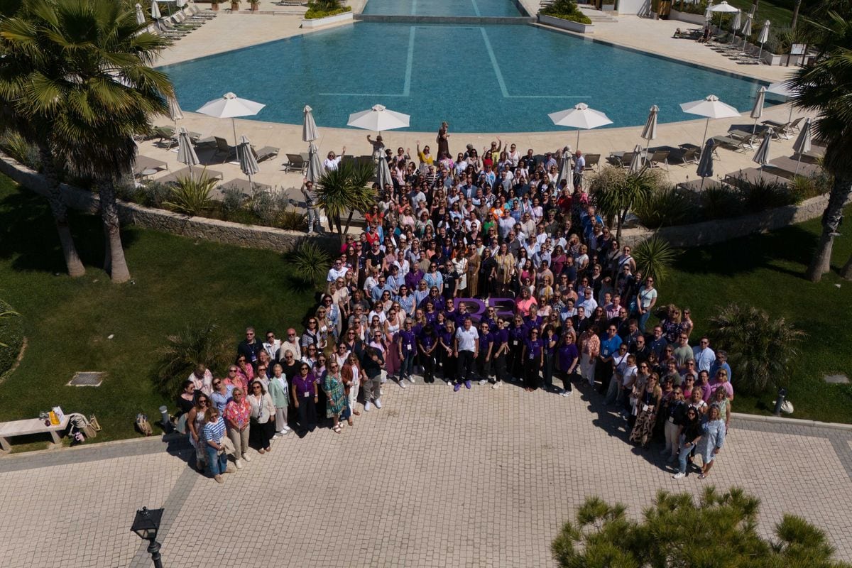 Viele Menschen stehen vor einem Pool. Eine Drohne fotografiert sie von oben
