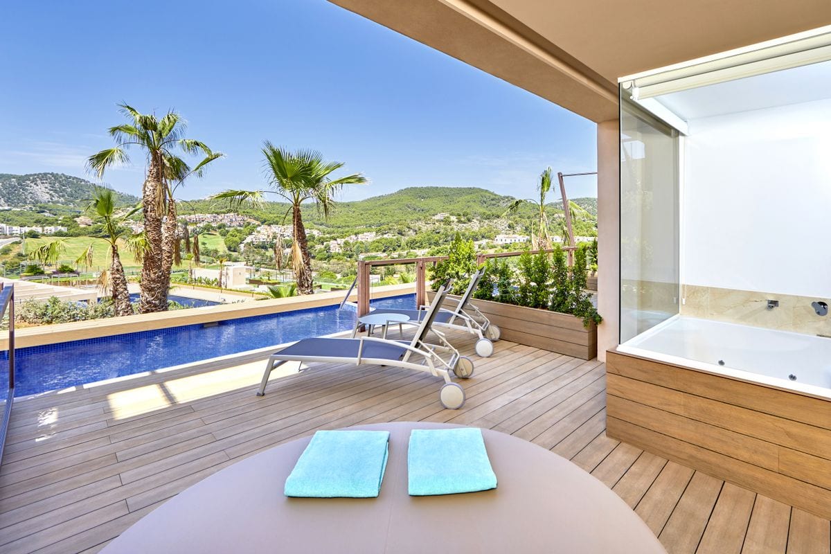 Auf dem Foto ist eine luxuriöse Terrasse mit privatem Pool, Sonnenliegen und Whirlpool zu sehen, umgeben von Palmen und mit Blick auf grüne Hügel.
