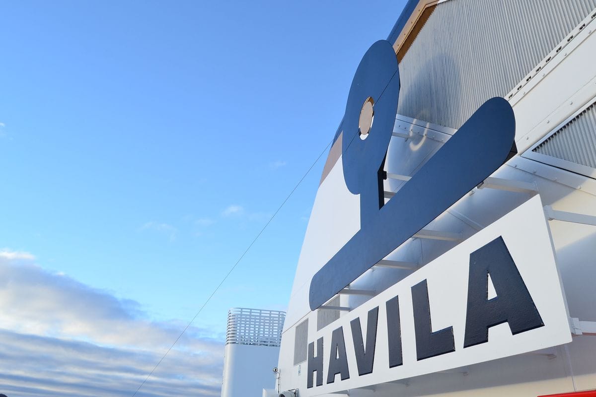 Schornstein eines Havila-Postschiffs mit großem Havila-Schriftzug vor blauem Himmel.