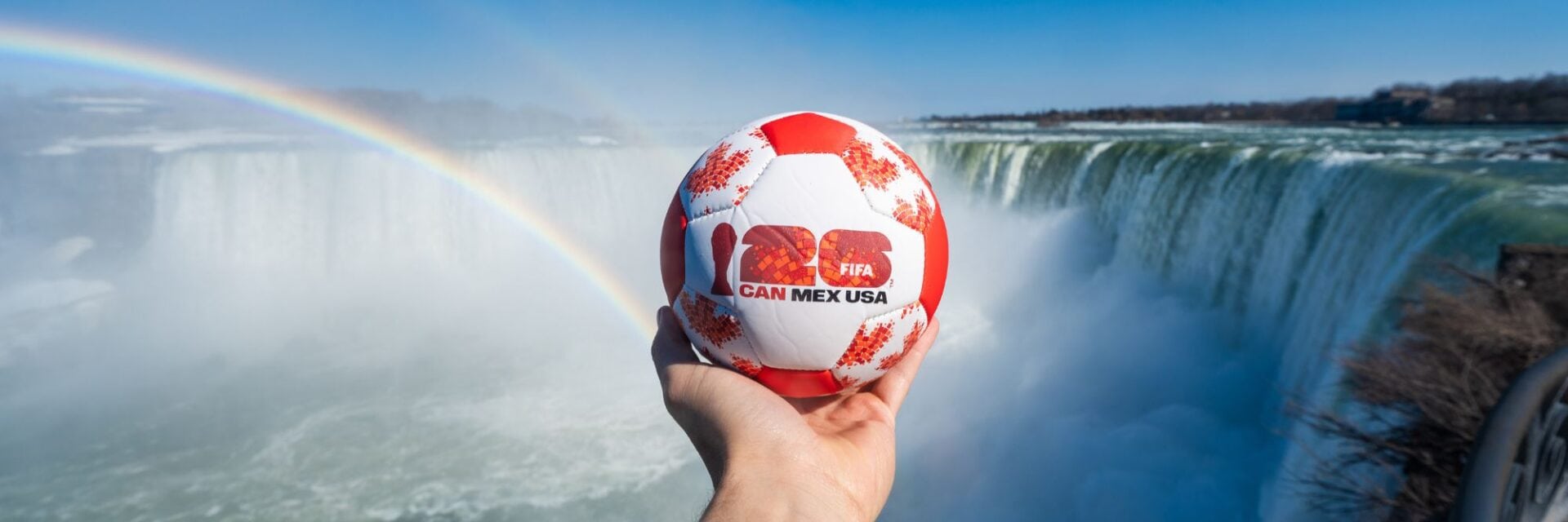 Ein Fußball wird vor den Niagarafällen gehalten, während die Vorfreude auf das Public Viewing zur Fußball-WM steigt.