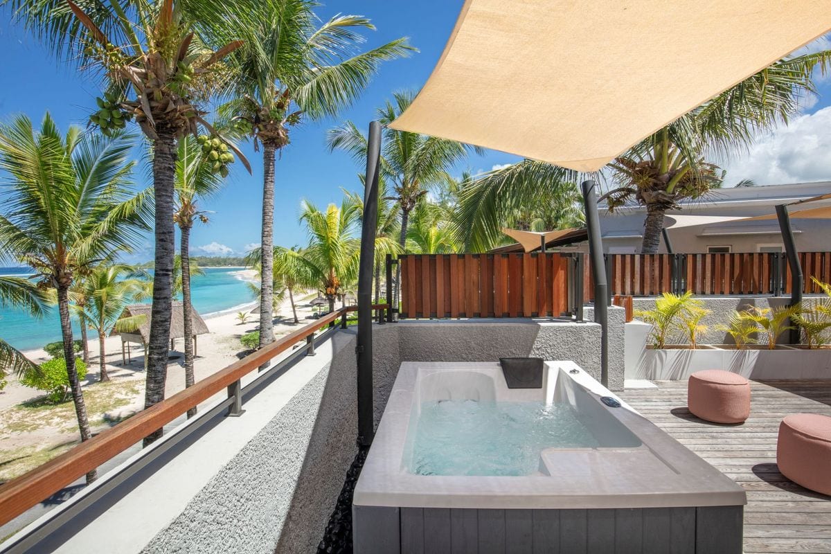 Blick auf das renovierte Beachcomber Shandrani mit Whirlpool und Palmen, umgeben von einem schönen Strand.