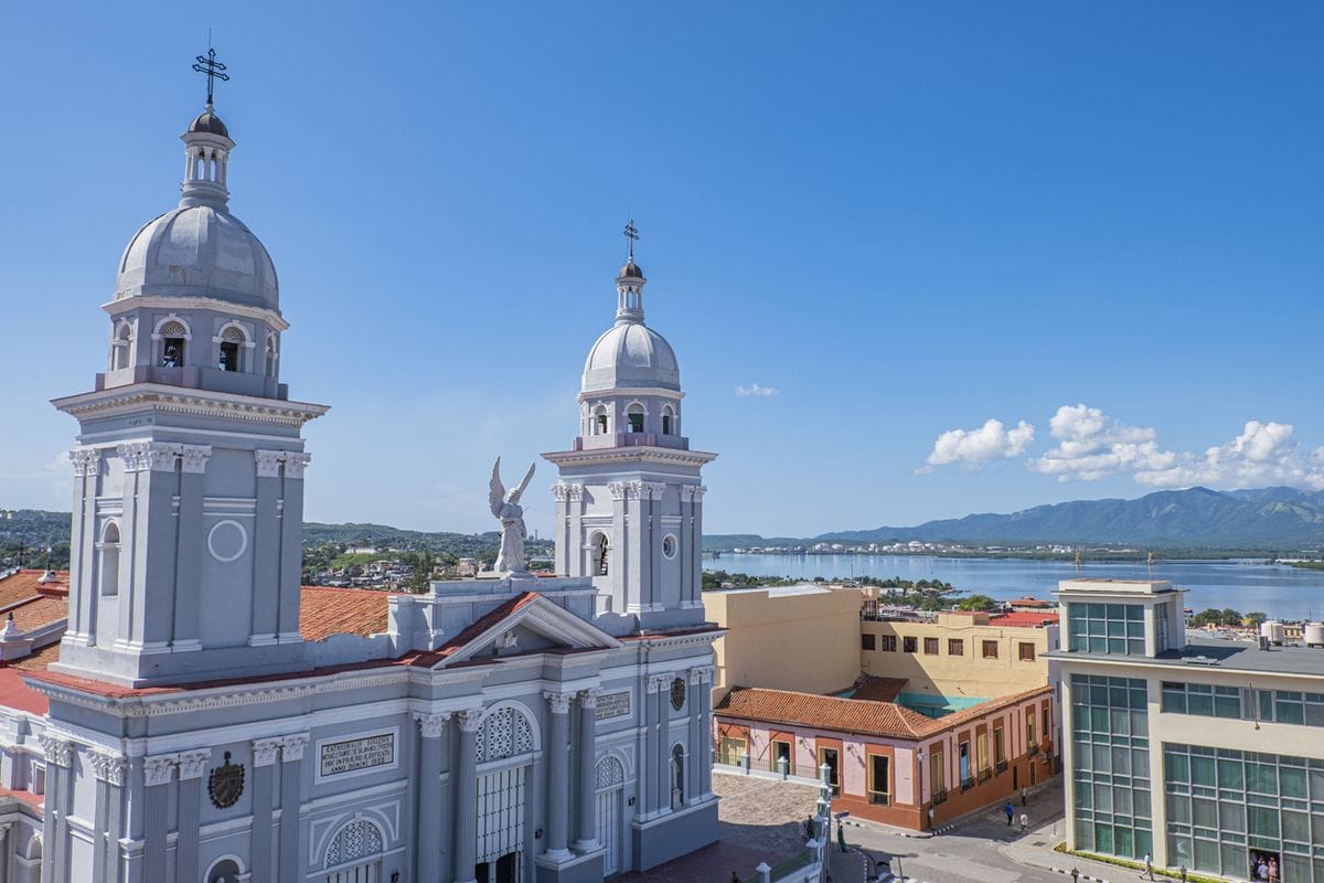 Blick auf die Kathedrale in Santiago de Cuba und die umliegende Stadtlandschaft in Kuba, mit klarer Sicht auf den Himmel und das Wasser.