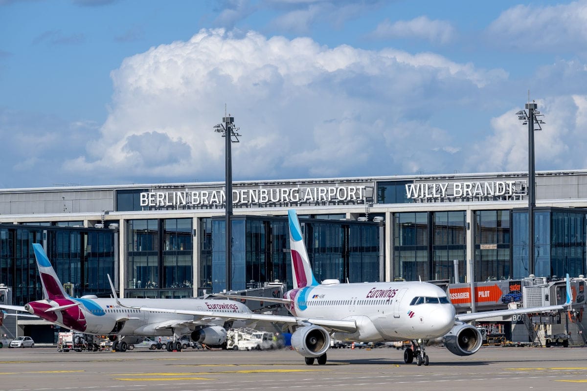 Eurowings-Flugzeuge am Flughafen Berlin Brandenburg mit moderner Architektur im Hintergrund und einem klaren blauen Himmel.