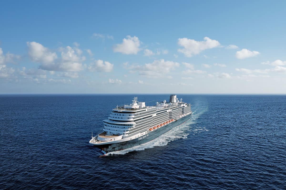 Ein großes Kreuzfahrtschiff fährt durch ruhige, blaue Gewässer unter einem klaren Himmel mit wenigen Wolken.