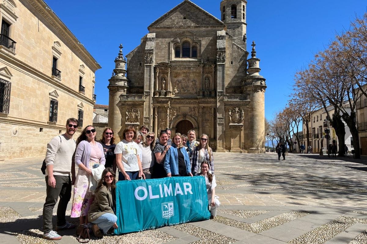 Gruppe von Reisebüro-Expedienten posiert vor einer historischen Kirche in einer Stadt mit klar blauem Himmel.