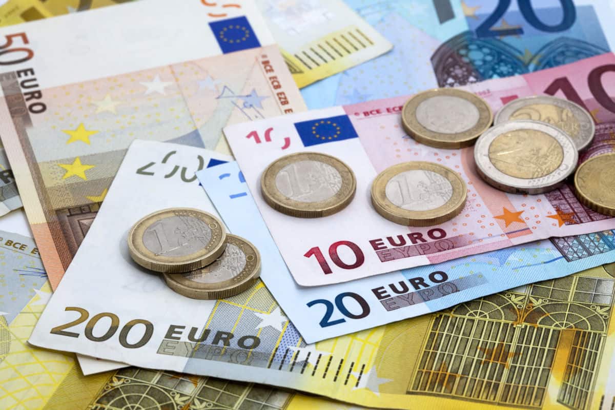 Eine Ansammlung von Euro-Banknoten in verschiedenen Stückelungen sowie Münzen, die auf einem Tisch liegen. Die Banknoten sind farbenfroh und gut sichtbar.