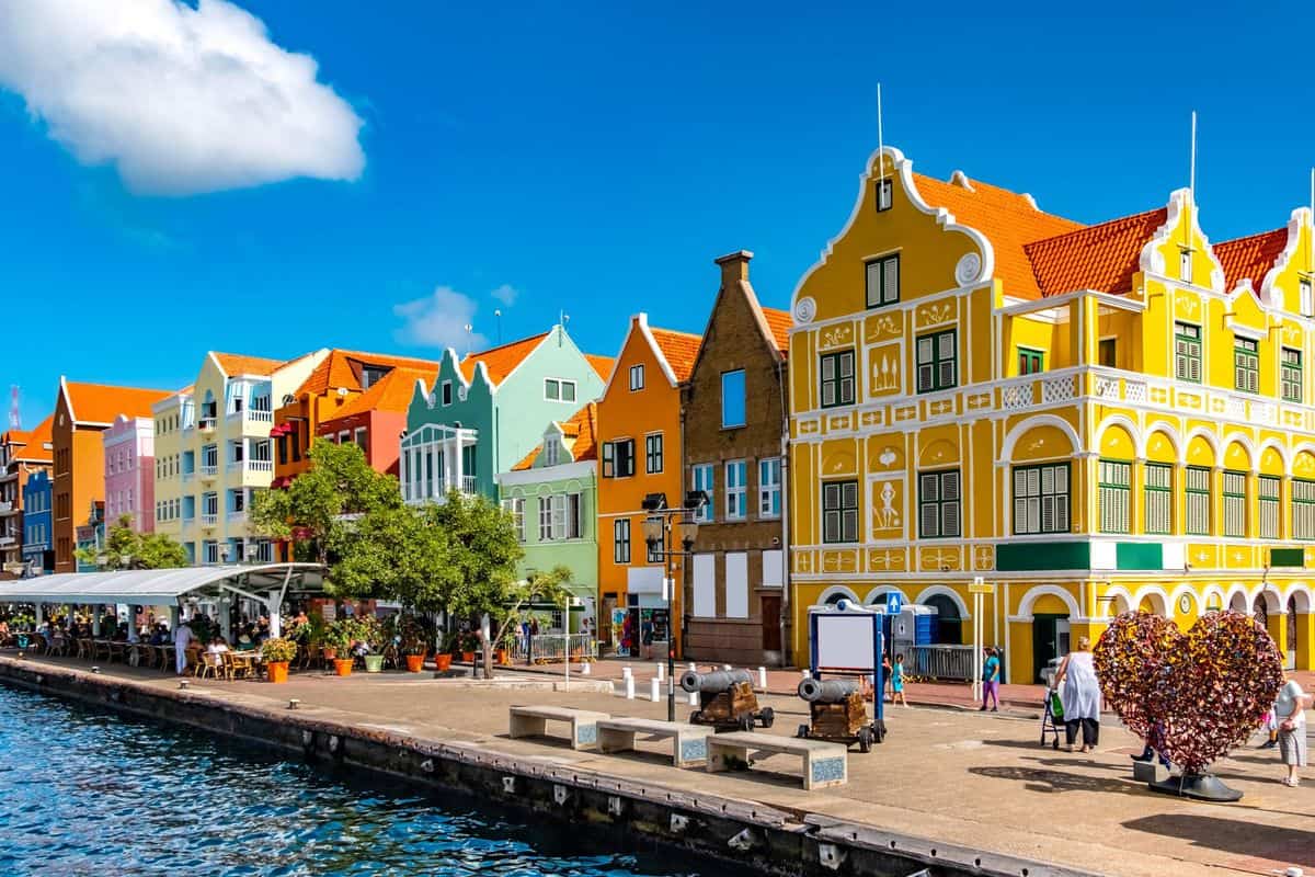 Bunte, historische Gebäude am Wasser mit einem klaren blauen Himmel im Hintergrund, ideal für Reisefotografie und Stadtansichten.