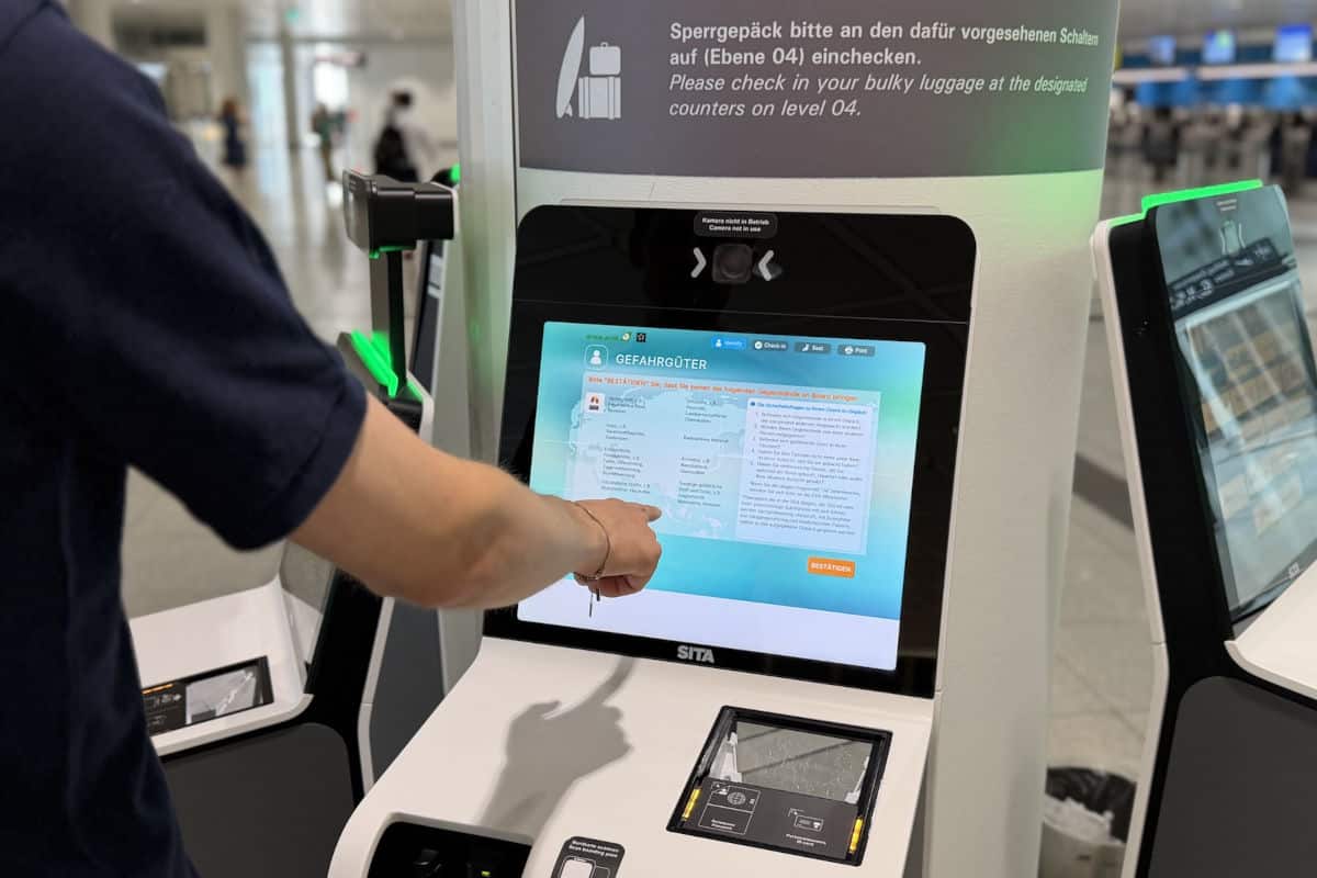 Ein Reisender nutzt einen Selbstbedienungsterminal am Flughafen, um Informationen zum Einchecken von Gepäck abzurufen.