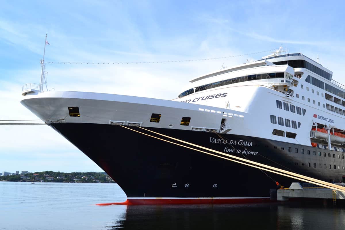 Ein großes Kreuzfahrtschiff mit dem Namen Vasco da Gama liegt an einem Hafen, umgeben von ruhigem Wasser und einem klaren Himmel.