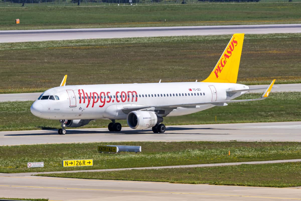 Ein Flugzeug von Pegasus Airlines steht auf dem Rollfeld, mit klarer Sicht auf die Tragflächen und das Heck, umgeben von grünem Gras.