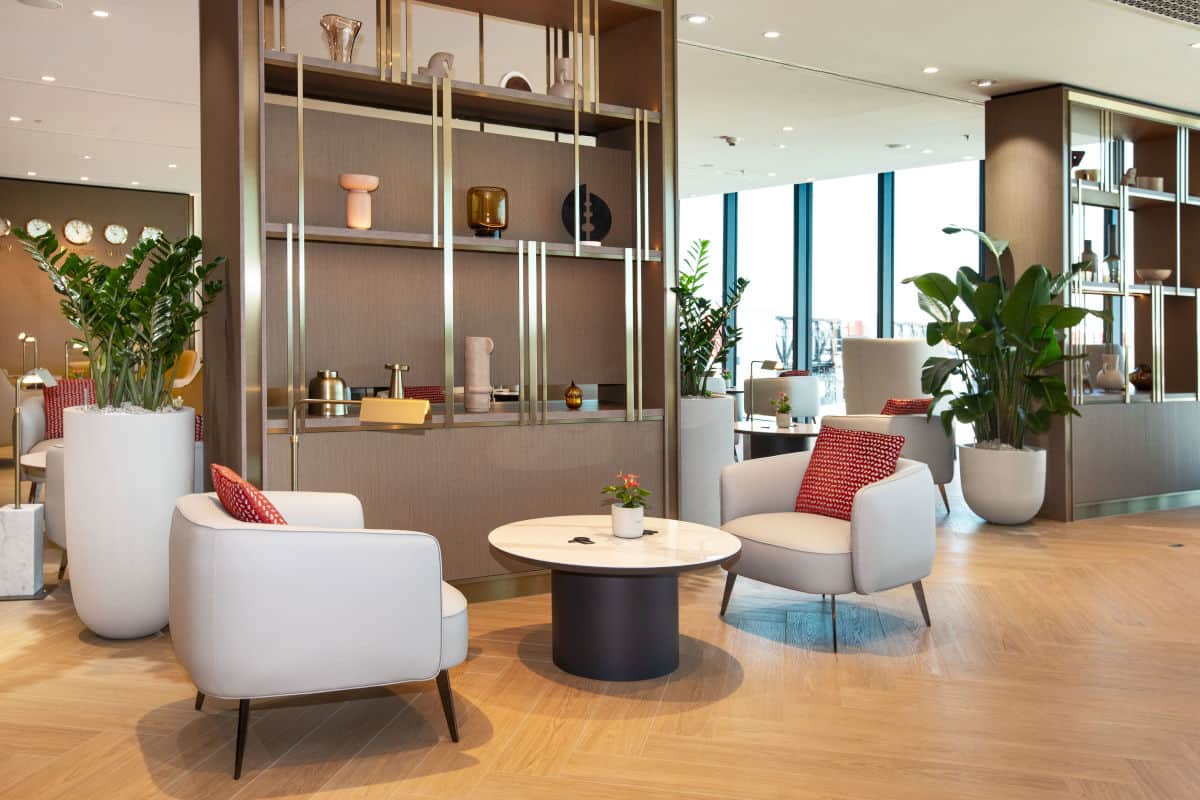 Moderne Lounge von Emirates am Flughafen Frankfurt mit zwei bequemen Sesseln, einem runden Tisch und Pflanzen in eleganten Töpfen, umgeben von stilvollem Interieur.