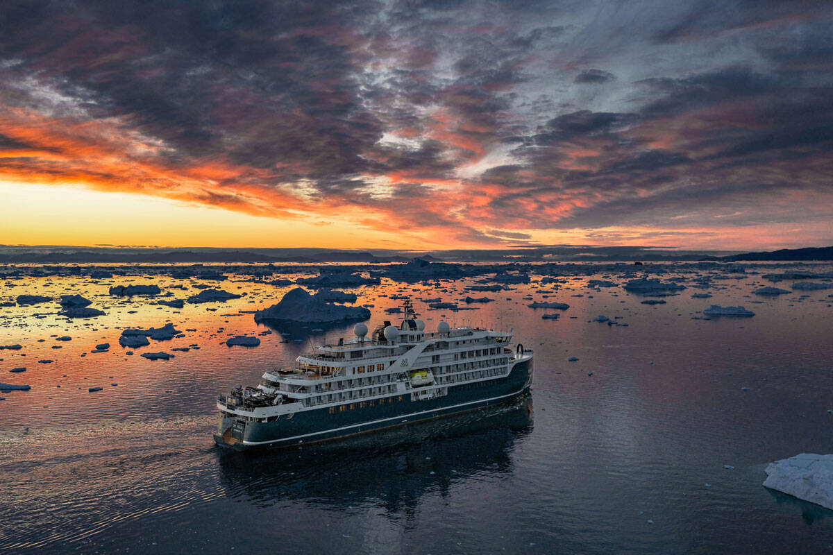 Ein Kreuzfahrtschiff fährt durch ruhige Gewässer, umgeben von Eisbergen und einem farbenfrohen Sonnenuntergang am Horizont.