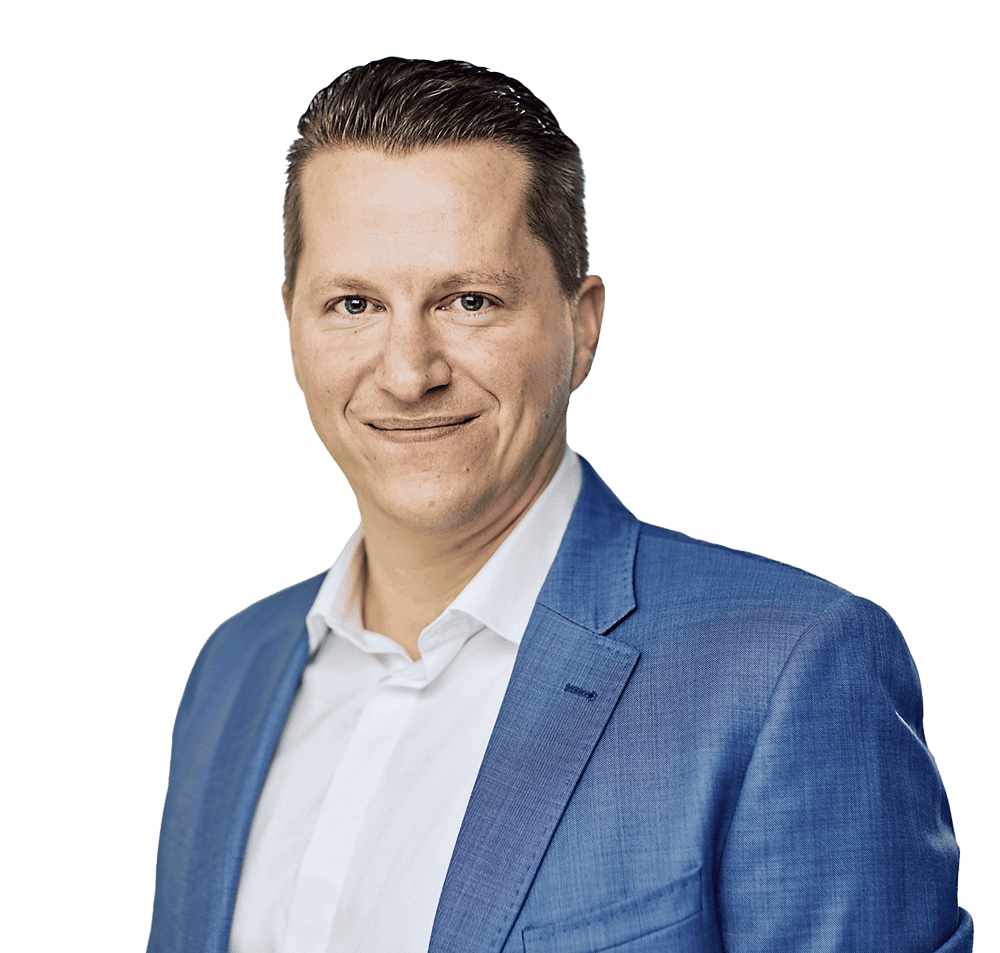 jacobi-benjamin-foto_tui-1000-953 Ein Mann mit kurzen, dunklen Haaren und einem freundlichen Lächeln trägt einen hellblauen Anzug und ein weißes Hemd. Der Hintergrund ist unscharf.