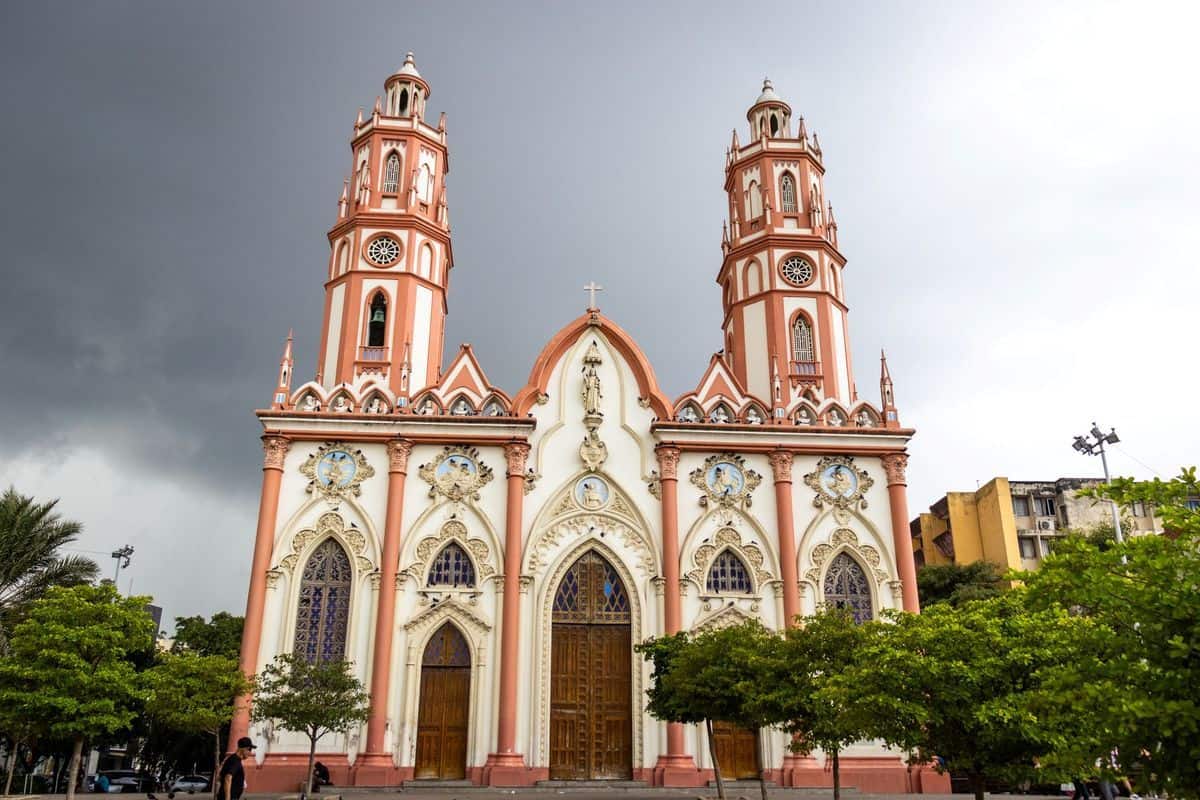Die prachtvolle Fassade der Kirche Iglesia de San Nicolás de Tolentino in Barranquilla mit zwei markanten Türmen unter einem bewölkten, grauen Himmel.