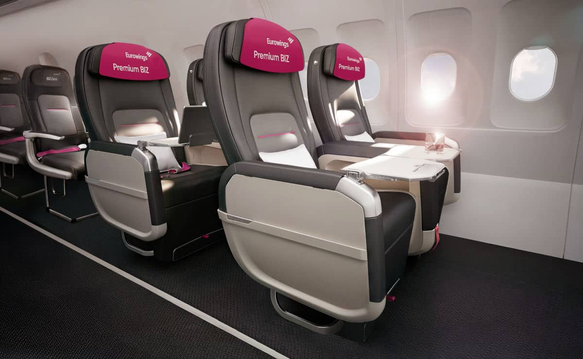 Innenansicht einer Flugzeugkabine mit dunkelgrauen Ledersitzen der Eurowings Premium BIZ Klasse, die in einer Reihe angeordnet sind und Fenster zeigen.