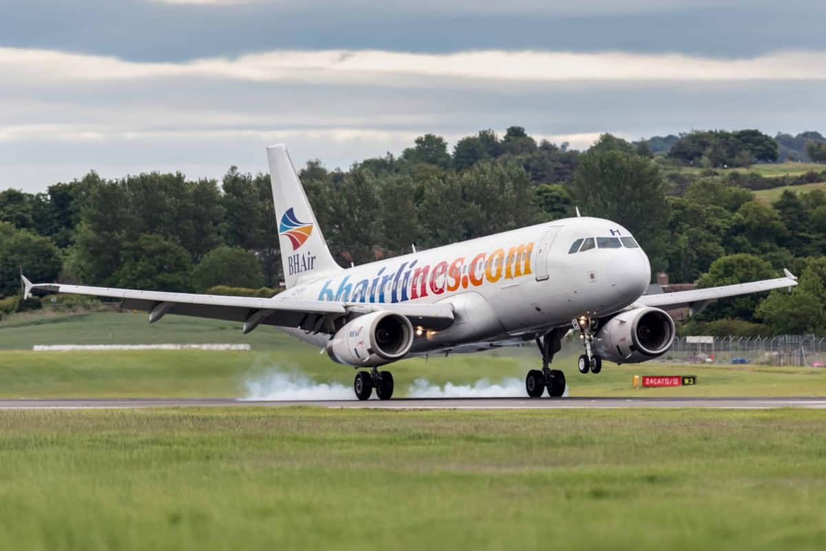 Ein Verkehrsflugzeug der Fluggesellschaft BH Air setzt bei der Landung auf einer asphaltierten Start- und Landebahn auf, wobei Reifenspuren sichtbar sind.