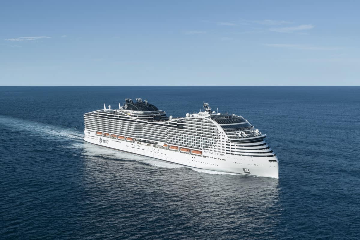 Das Kreuzfahrtschiff MSC World Europa fährt auf dem offenen Meer und hinterlässt eine deutlich sichtbare Bugwelle auf der tiefblauen Wasseroberfläche.
